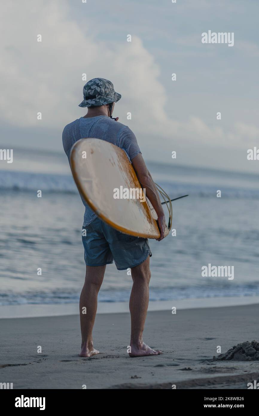surfer carrying board while looking at the horizon Stock Photo