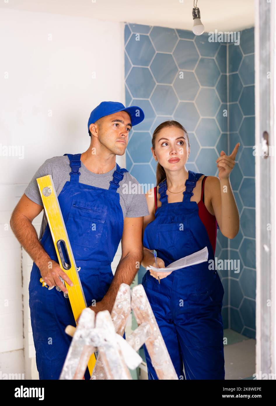 Repairers in overalls planning works in bathroom Stock Photo Alamy
