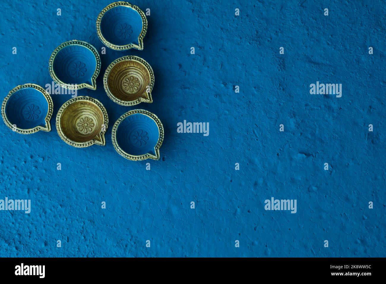 Blue and golden color traditional clay oil lamps Diya arranged on blue color background. Concept for Diwali, Deepavali, Pooja, prayer, worship. Stock Photo