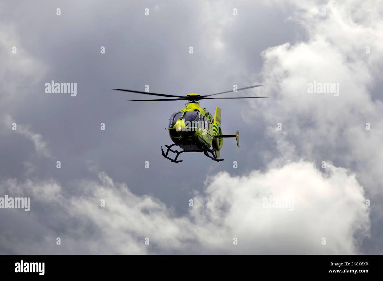 FinnHEMS medical helicopter in flight against dramatic cloudy sky. FinnHEMS is an abbreviation for Finnish Helicopter Emergency Medical Services. Stock Photo