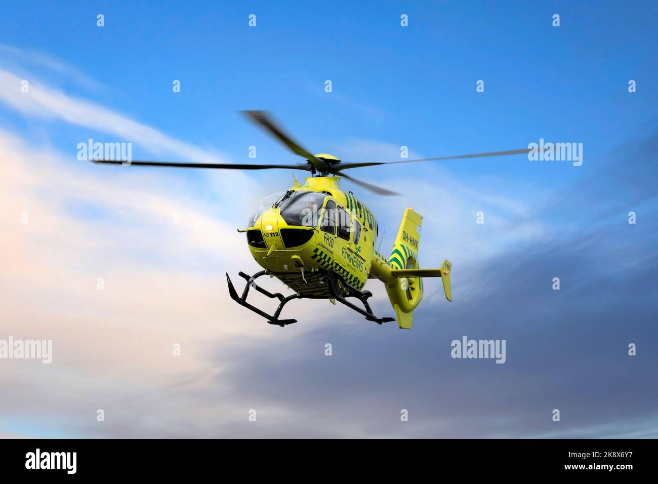 FinnHEMS, Finnish Helicopter Emergency Medical Services, medical helicopter takes off against blue sky and clouds. Stock Photo