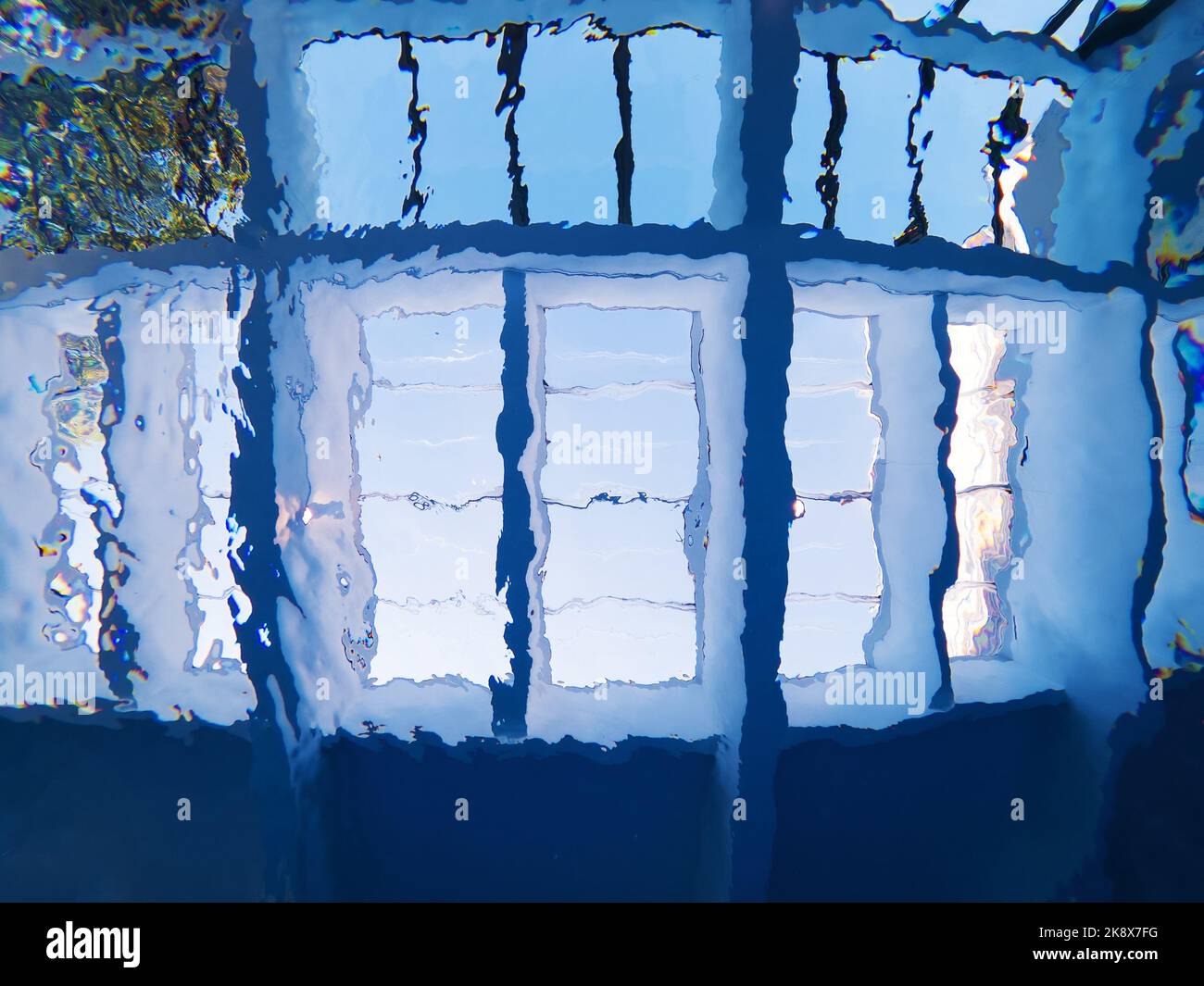 Glass roof of indoor swimming pool seen from underwater through rippled water surface as abstract background Stock Photo