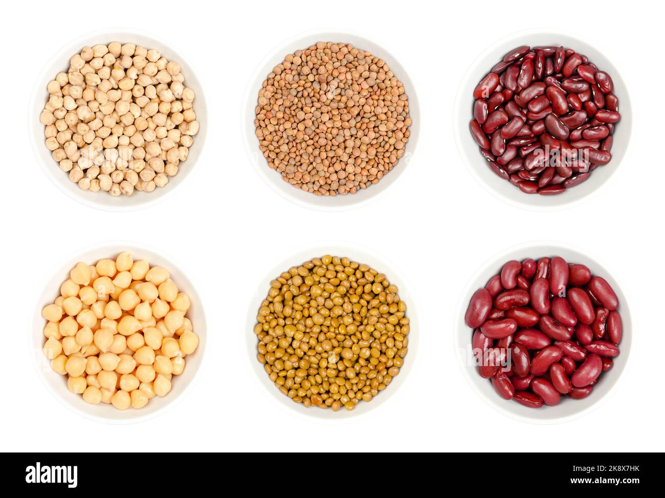 Dried and canned chickpeas, brown lentils and red kidney beans, in white bowls, isolated from above on white background. Raw and cooked seeds. Stock Photo