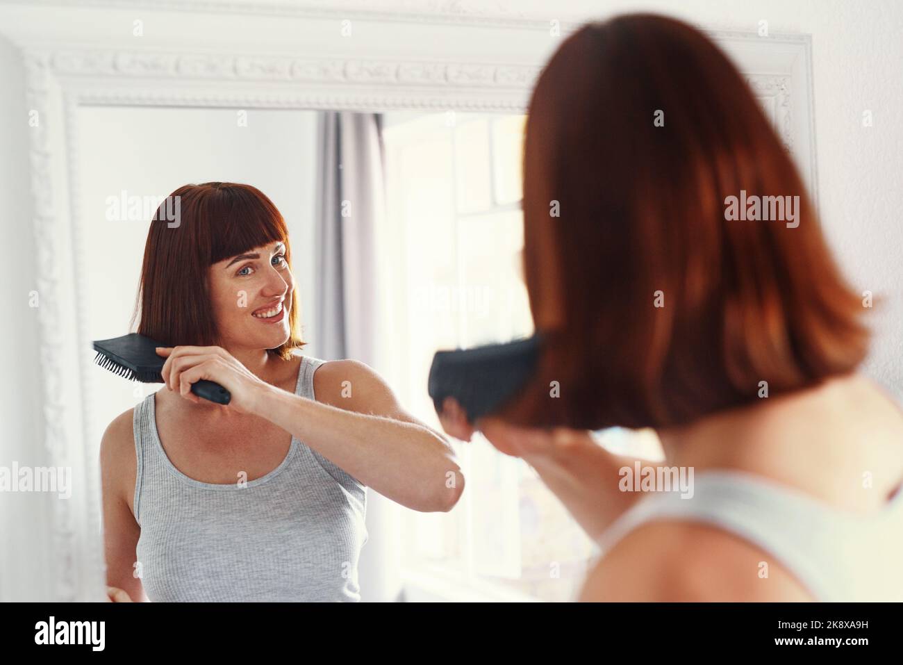 Someone is having a good hair day. an attractive young woman brushing her hair inside her bathroom at home. Stock Photo