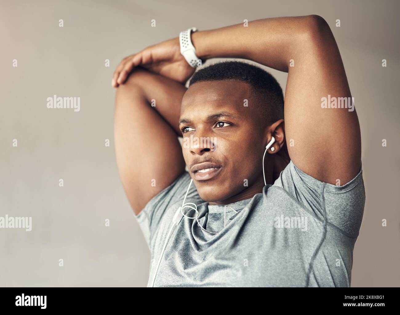 Your warmup makes all the difference. a sporty young man stretching his arms while exercising at home. Stock Photo