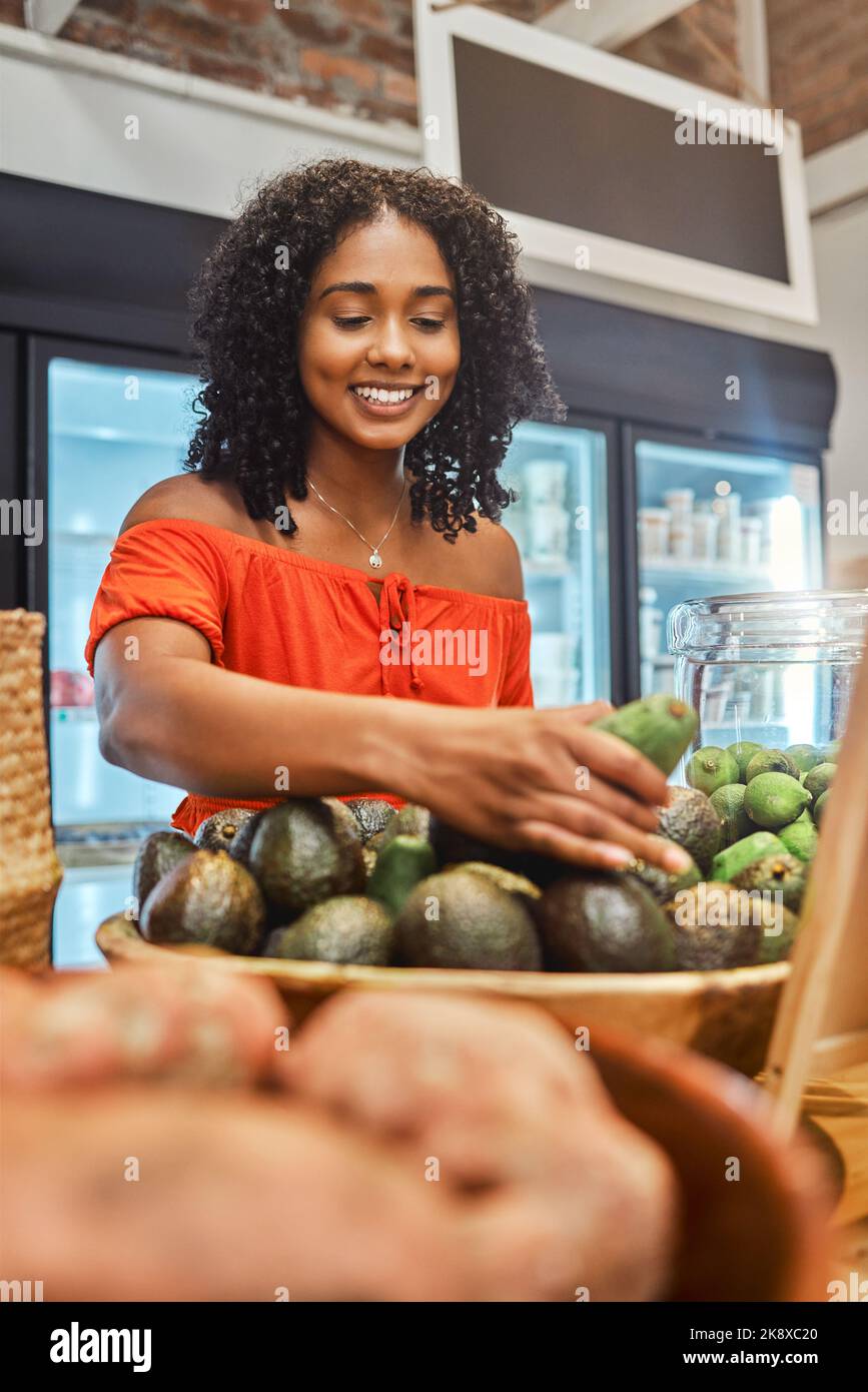 Black woman at supermarket, grocery shopping and avocado, customer and retail, vegetable fresh product and buying food at store. Young, African Stock Photo