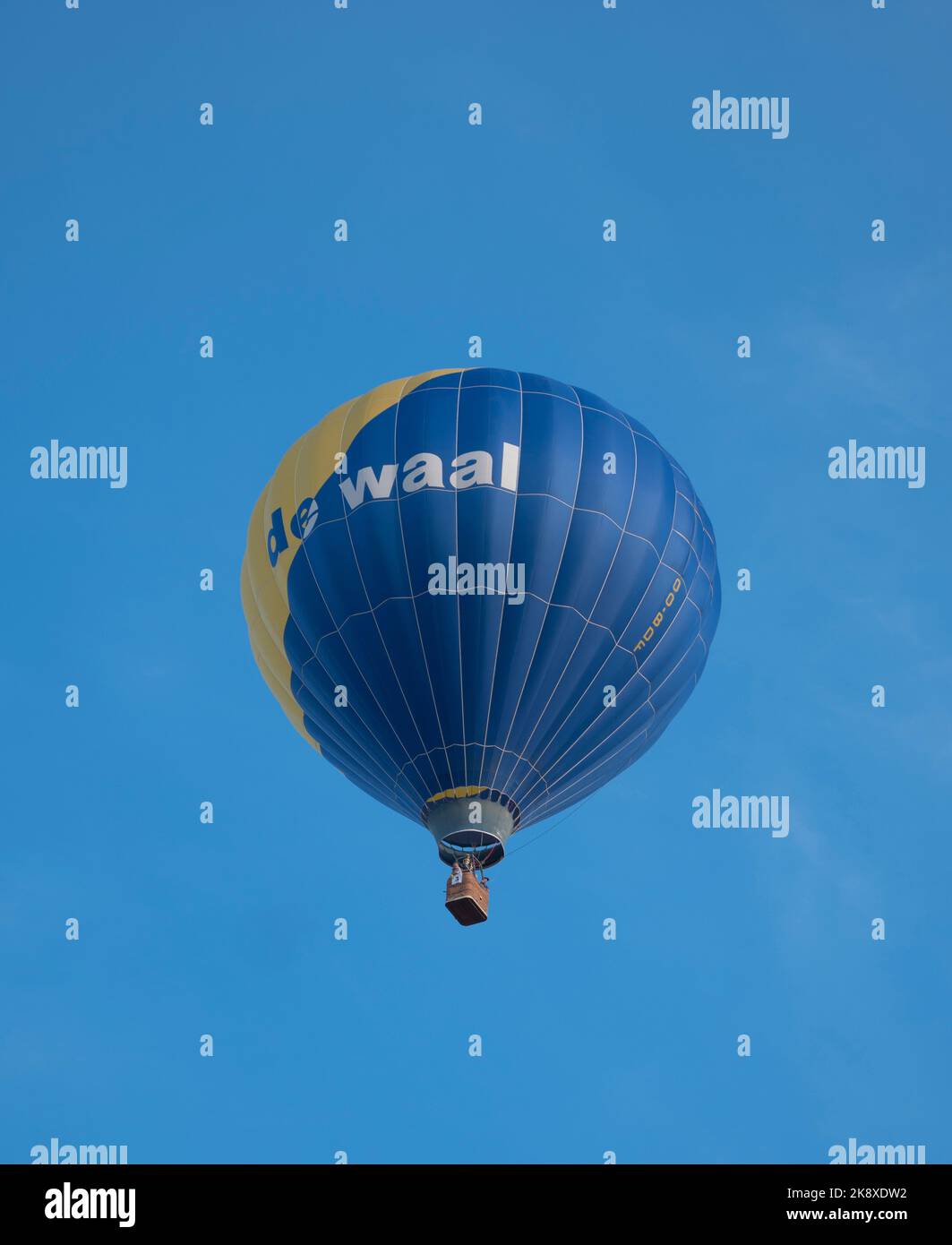 Sint Niklaas, Belgium, September 04, 2022, Blue yellow hot air balloon with small basket against a beautiful blue sky Stock Photo