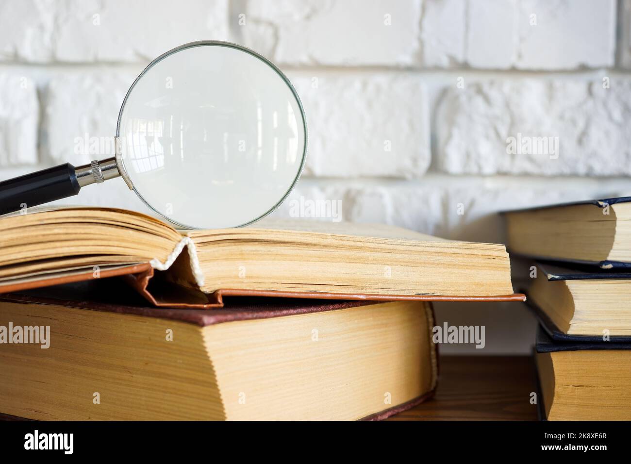 Magnifying glass on an open book as a concept of knowledge and research. Stock Photo