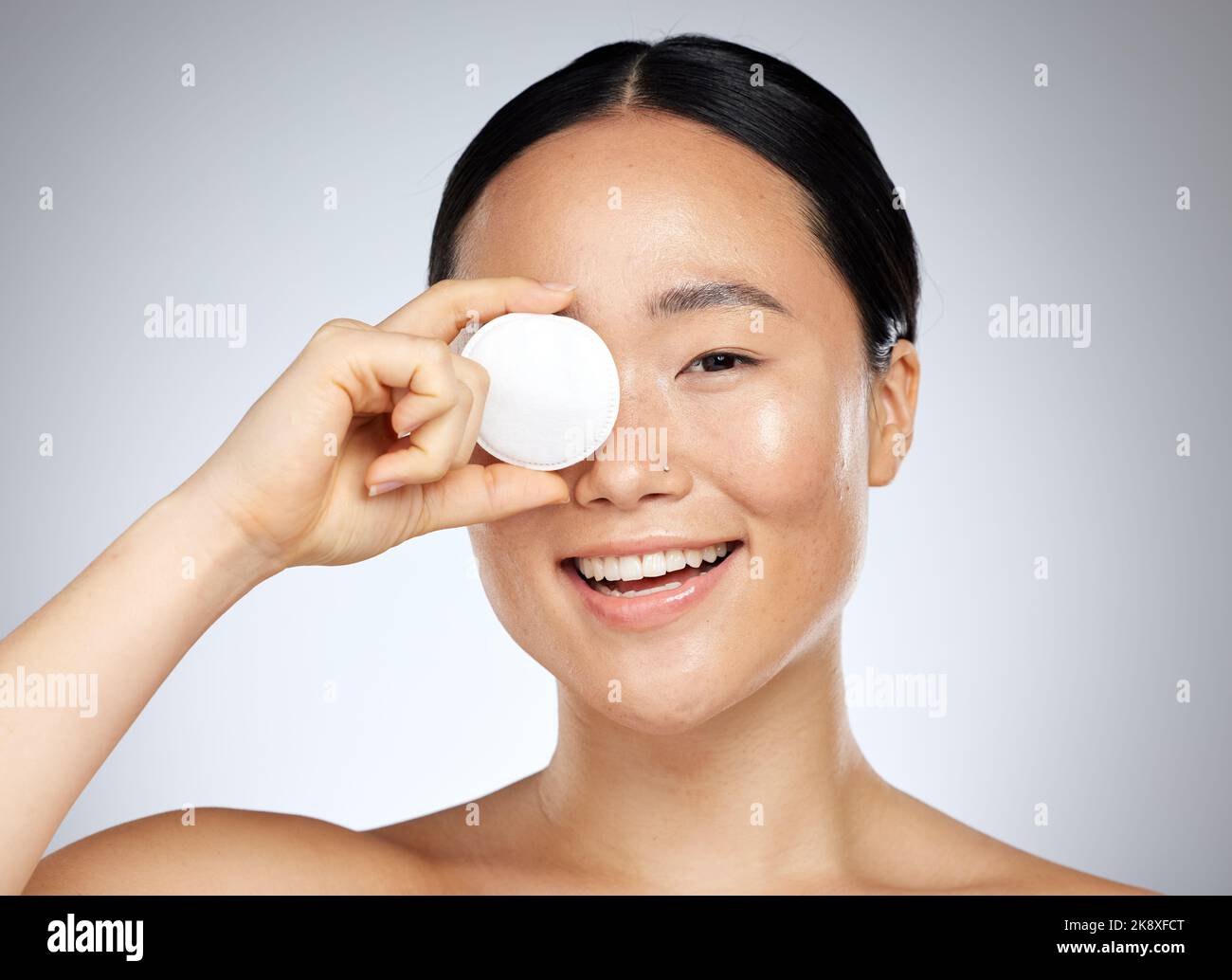 Skincare, beauty and woman with a cotton pad for cleaning, wellness and facial health against grey mockup studio background. Portrait of happy, relax Stock Photo