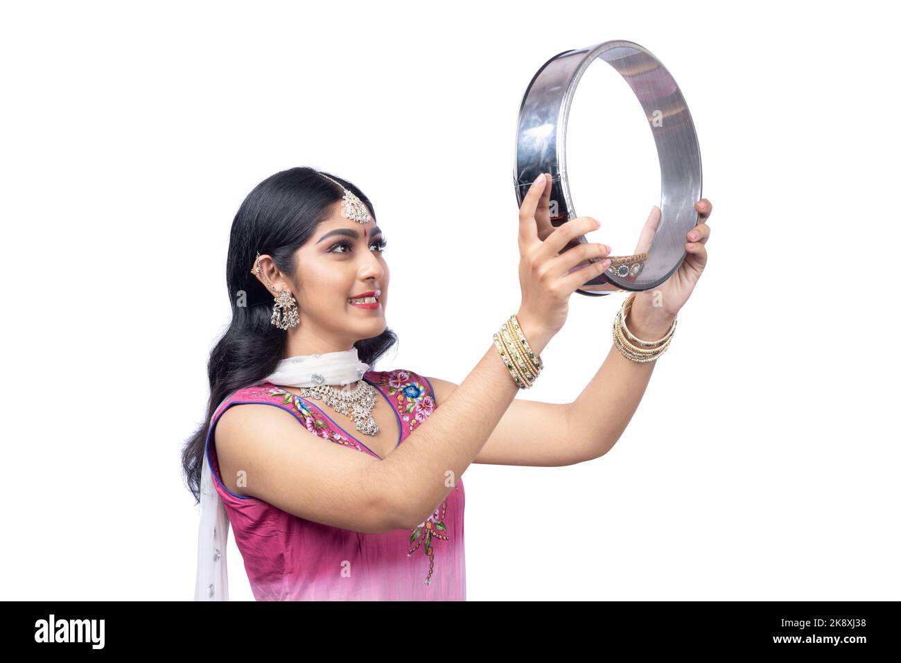 Indian woman holding Karwa Chauth strainer and Diya oil lamps for 