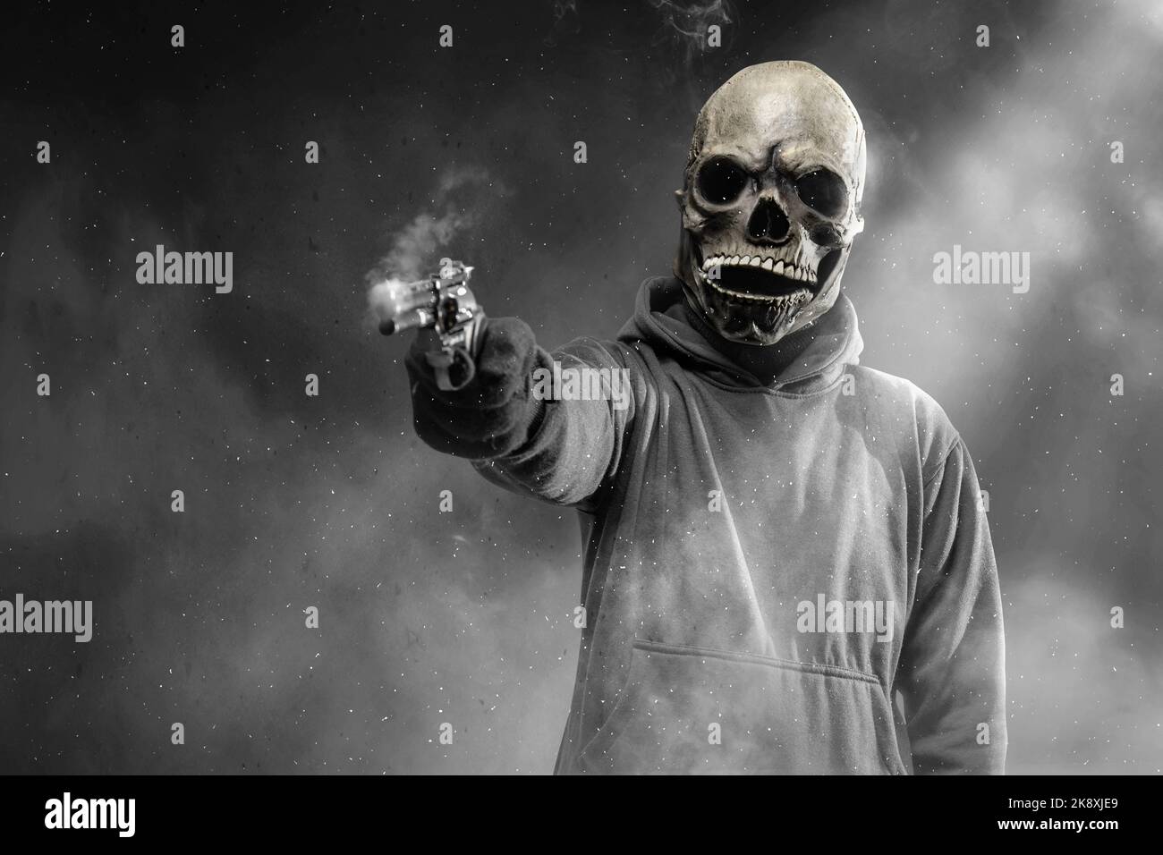 Man with a skull head costume holding gun and standing in the dark. Halloween concept Stock Photo