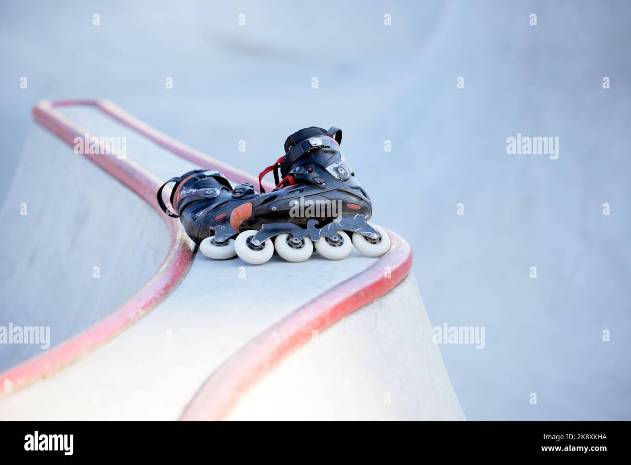 Pair of black inline skates lying on ramp at skate park. Sport