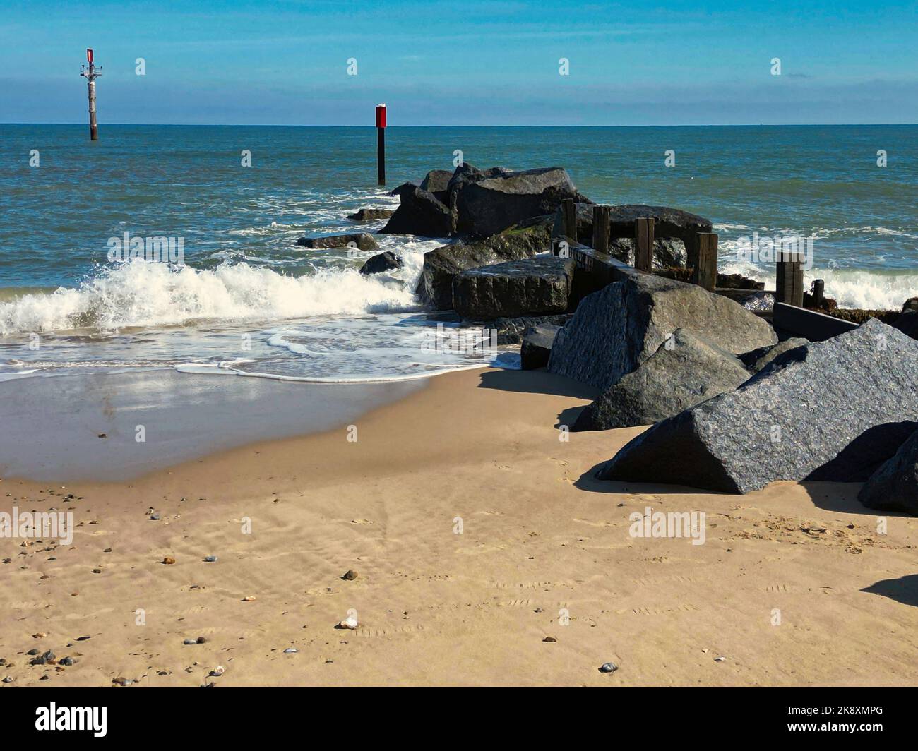 The coast of an ocean with foamy waves crashing on the sand on large ...