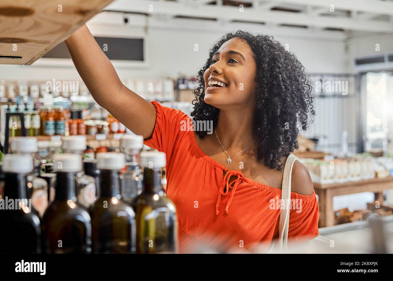 Supermarket, shelf and shopping customer woman retail store for eco friendly product, olive oil or groceries choice. Happy woman in small business Stock Photo