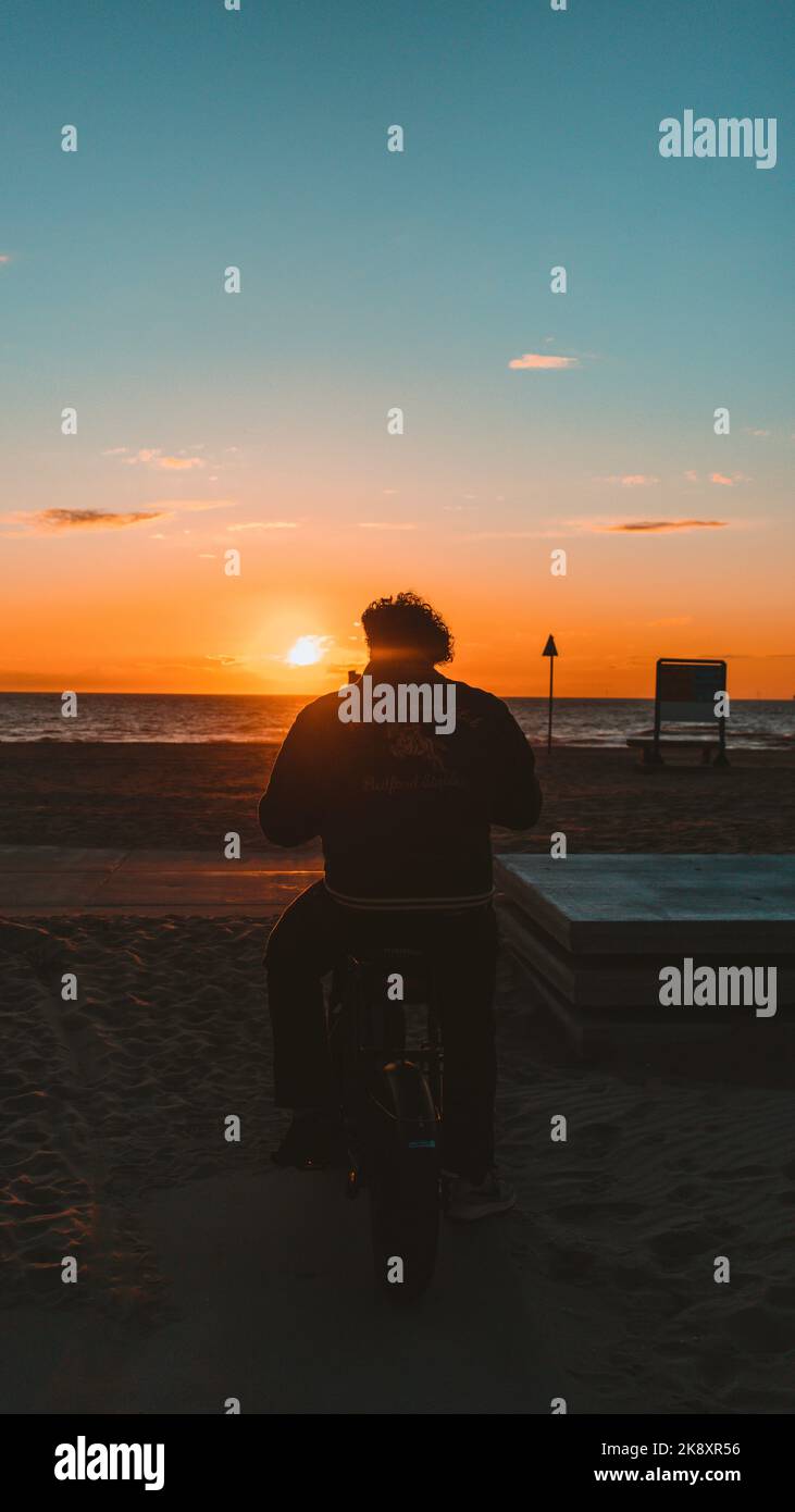 A silhouette of man watching sunset scenery from seashore Stock Photo ...