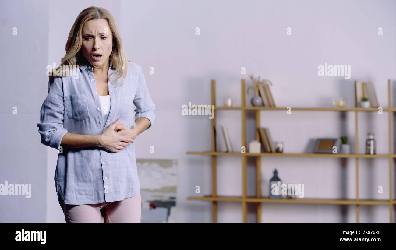 exhausted woman with opened mouth having stomach ache at home Stock