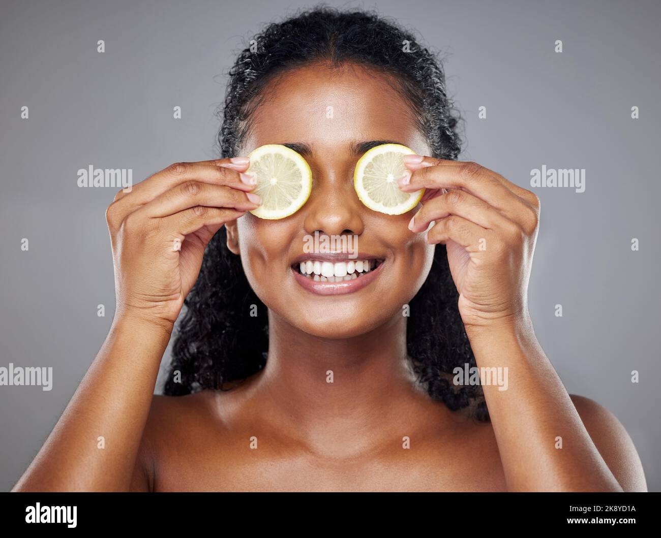 Skincare, portrait and woman with lemon on her eyes for health, beauty and wellness standing in a studio. Happy, smile and face of girl model from Stock Photo