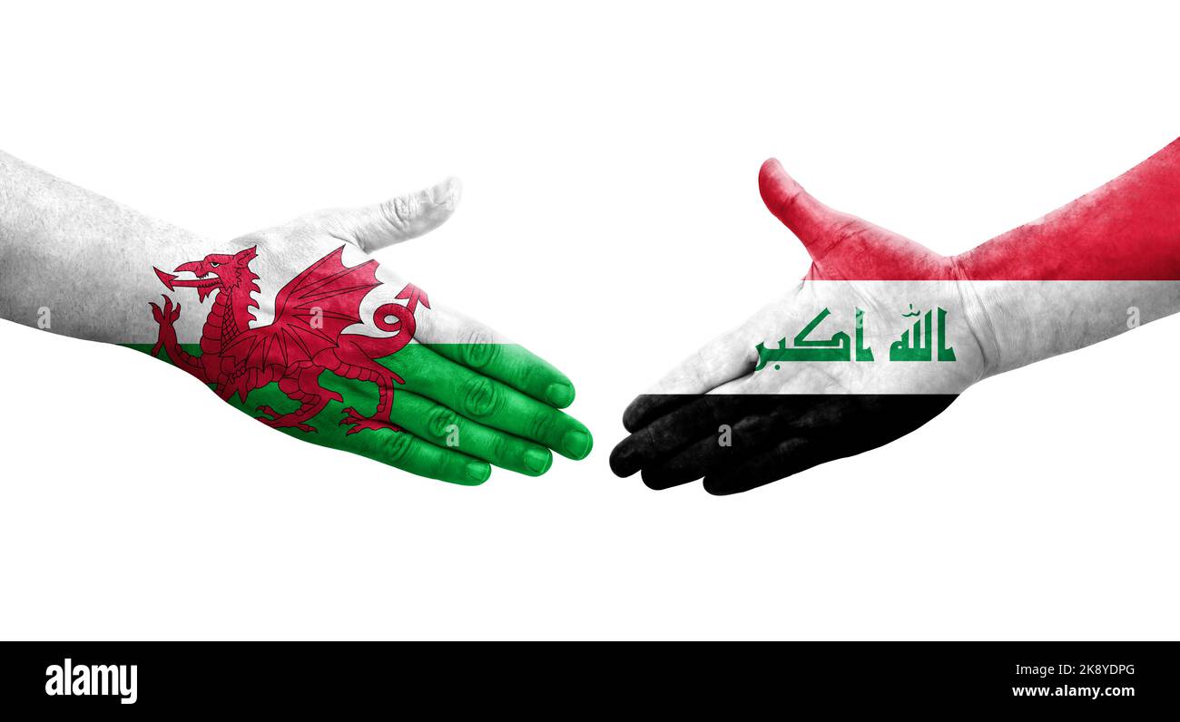 Handshake between Iraq and Wales flags painted on hands, isolated transparent image. Stock Photo