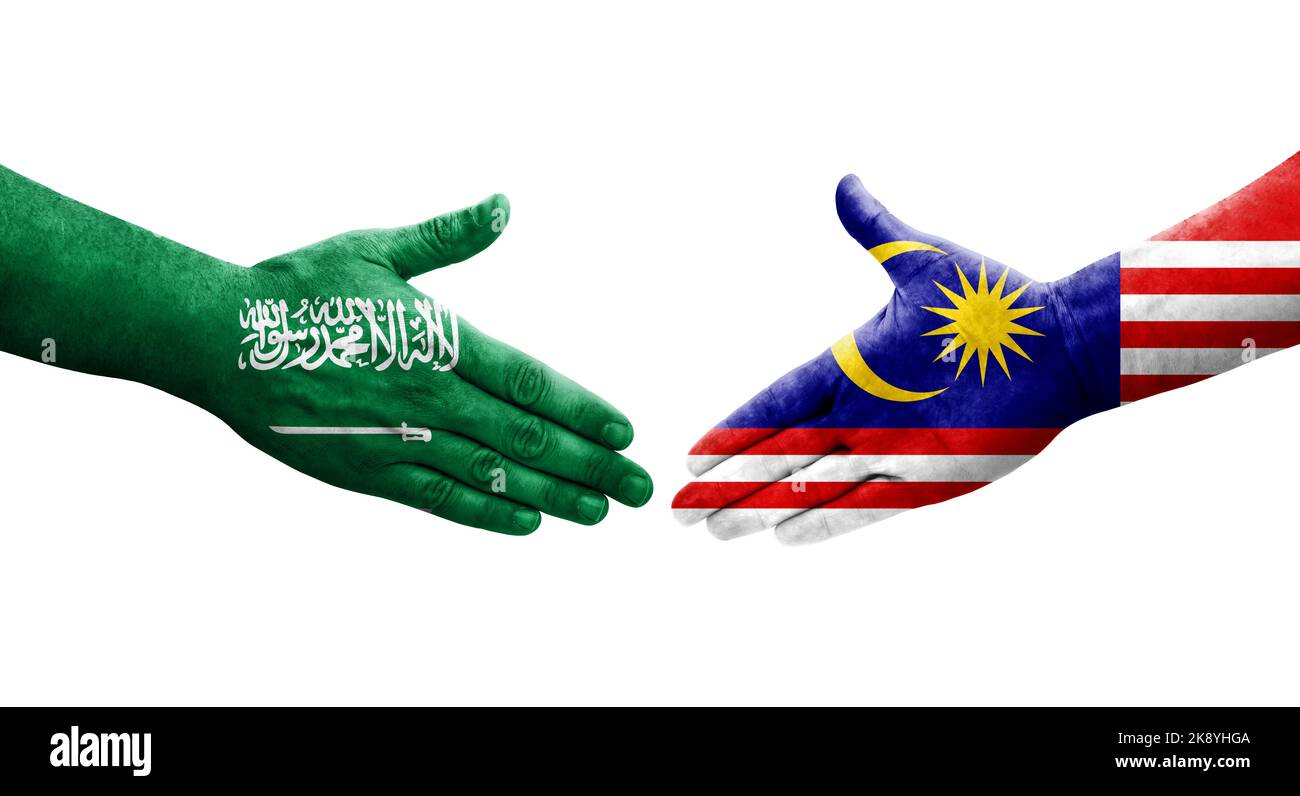 Handshake between Malaysia and Saudi Arabia flags painted on hands, isolated transparent image. Stock Photo
