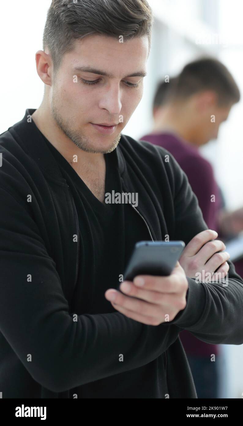 smiling young man reading a message on his smartphone. Stock Photo