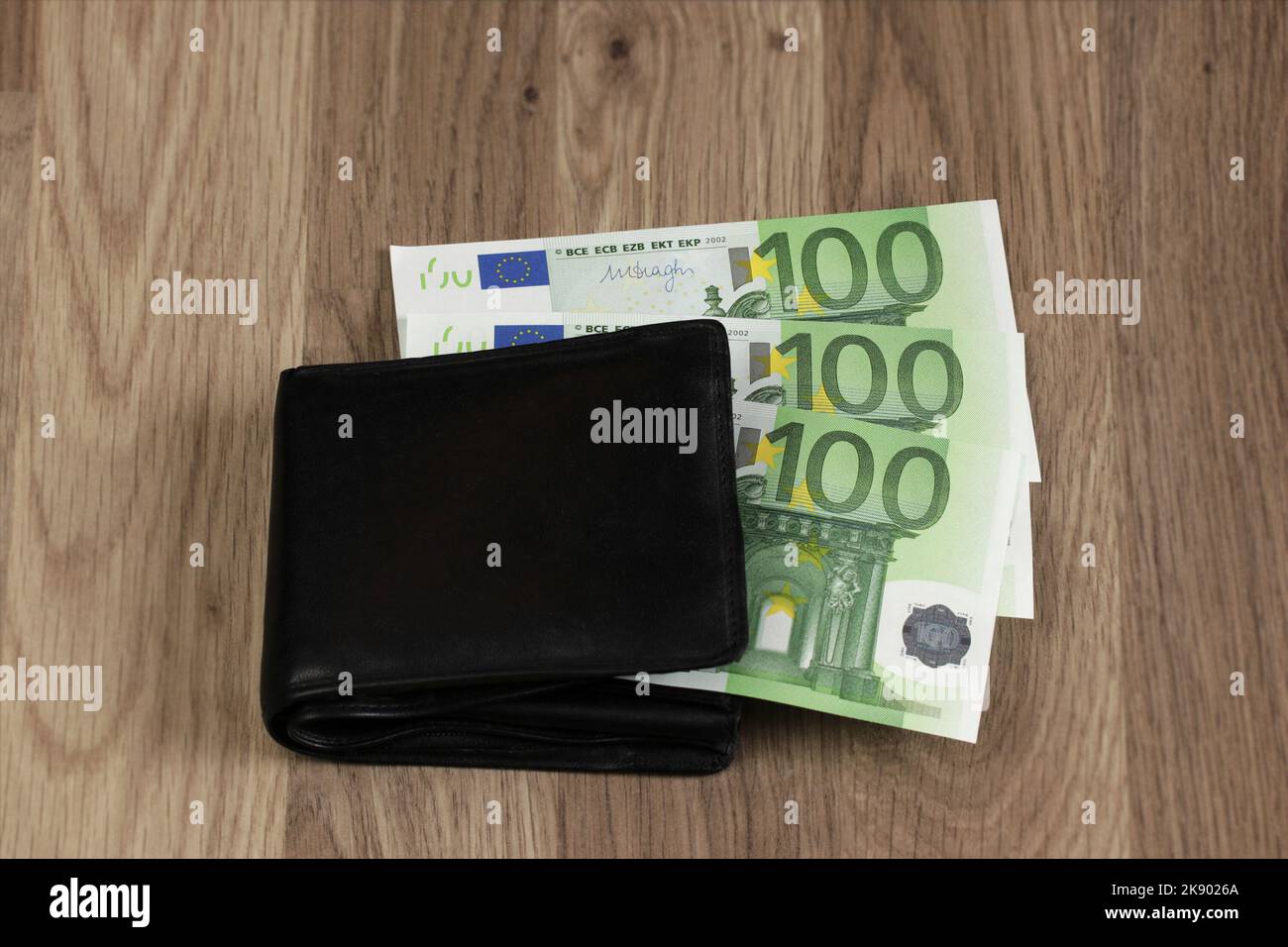 300 euros sticking out of the wallet. Three paper banknotes of 100 euros each. Symbol for growing expenses, inflation, paying household bills, salary. Stock Photo