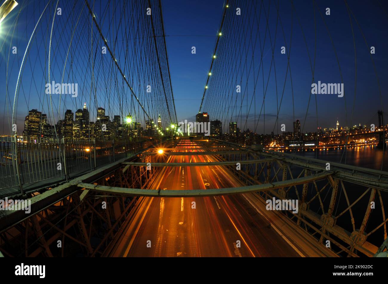 The suspender cables of Brooklyn Bridge and illuminated road at night. New York, USA. Stock Photo