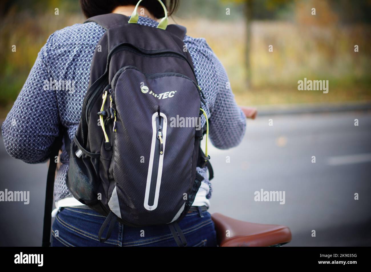 A woman wearing a Hi-Tec backpack with a bicycle by a road Stock Photo