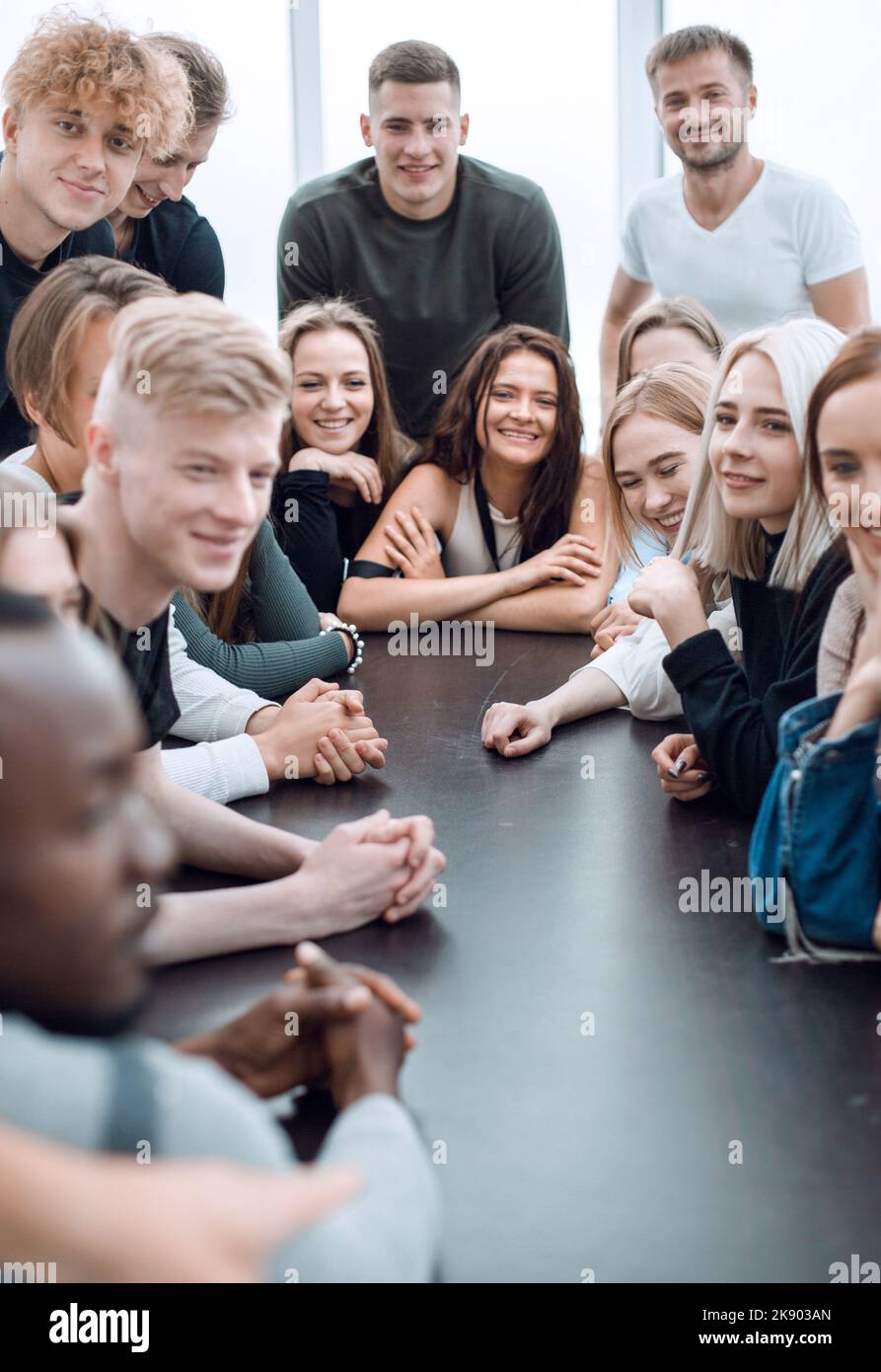 group of diverse young people sitting at a large table Stock Photo - Alamy