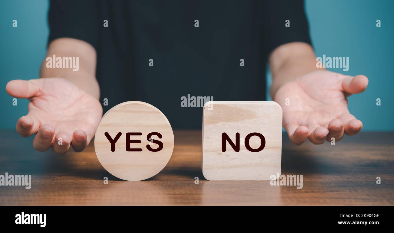 Yes or no choice symbol. Hand making a question gesture to choice between two cubes with Yes and No icon on the desk. Business and yes or no choice co Stock Photo