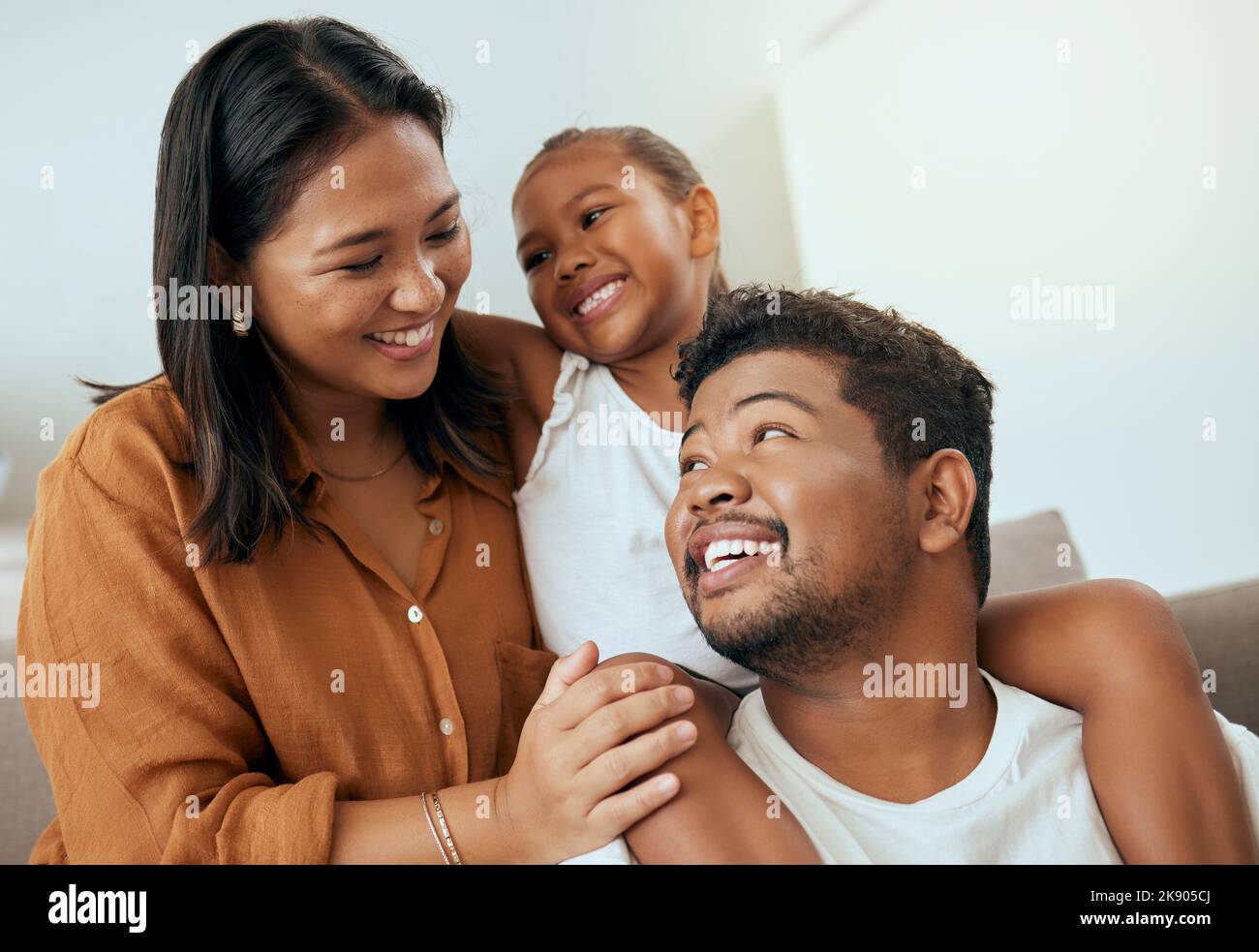 Love, family and relax on a sofa bonding, smile and embracing in a living room with happy, cheerful people. Happy family, quality time and child with Stock Photo