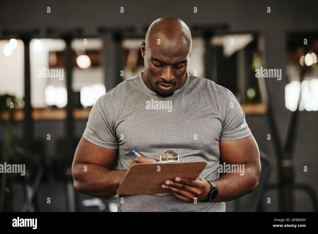 Black man, clipboard and writing in gym for training membership, sign ...