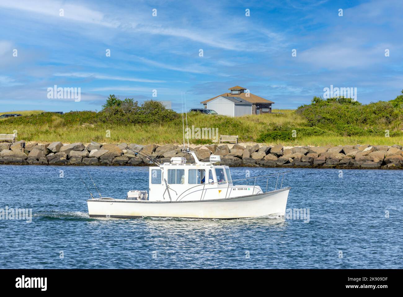 Small white fishing boat returning to Montauk harbor from a day on the water Stock Photo