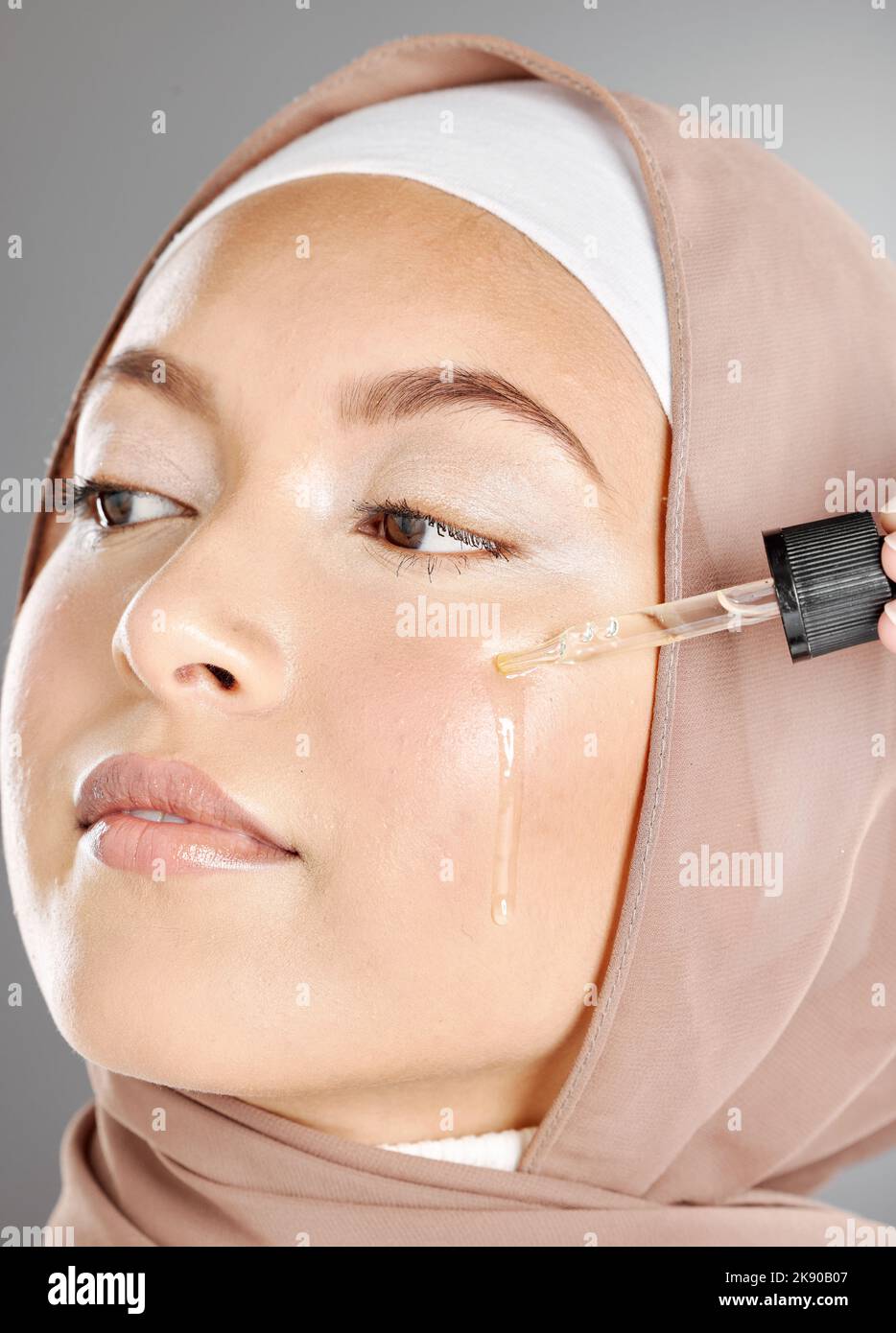 Muslim woman beauty, facial serum or essential oil, aesthetic makeup or glowing skincare on studio background. Islamic hijab girl, liquid cosmetic Stock Photo