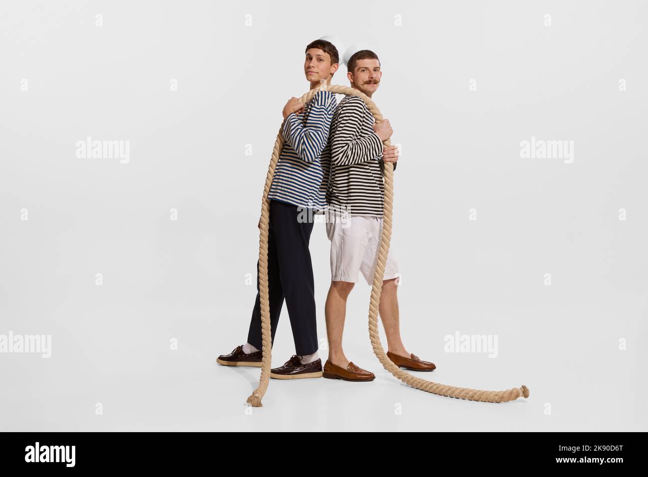 Portrait of two young boys, sailor, seamen in striped shirts holding ...