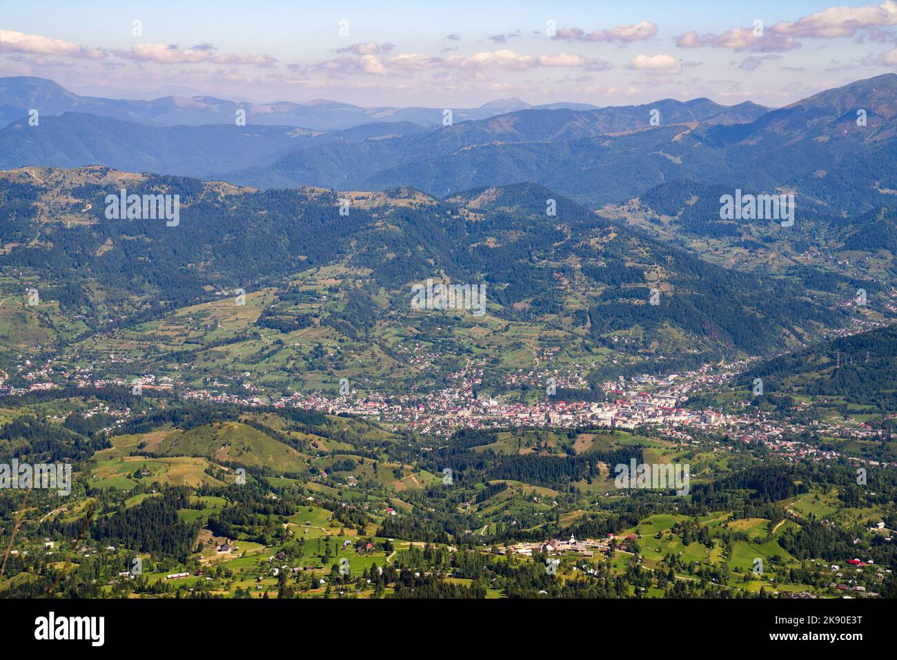An aerial breathtaking view of small town in green valley surrounded by ...