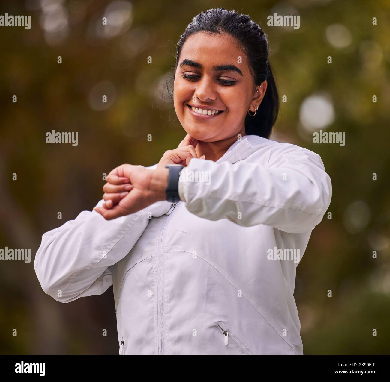 Pulse, fitness and woman running in the park, on a break to check heart rate on sports watch. Indian girl doing exercise, training and workout in Stock Photo