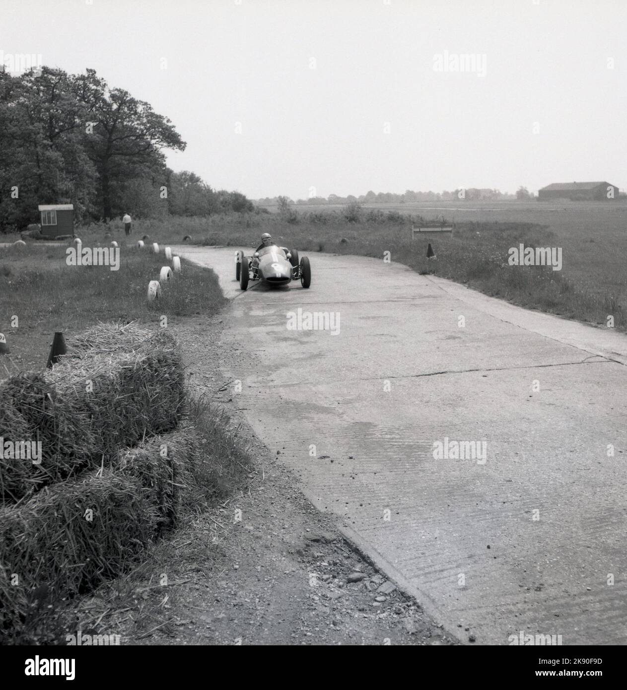 1962, historical, a single-seater racing car on the track, the perimeter road,  at the Finmere Aerodome, a disused RAF airfield near to Buckingham, England, UK, home to Geoff Clarke’s Motor Racing Stables. The racing school’s 1,000 cc single-seaters were rear-engined Formula Junior Coopers. Stock Photo