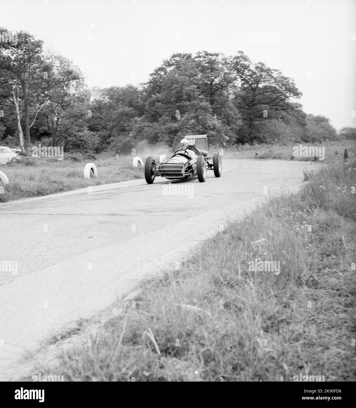 1962, historical, a single-seater racing car on the perimeter road circuit at the Finmere Aerodome, a disused RAF airfield near to Buckingham, England, UK, home to Geoff Clarke’s Motor Racing Stables. The racing school’s 1,000 cc single-seaters were rear-engined Formula Junior Coopers. Stock Photo