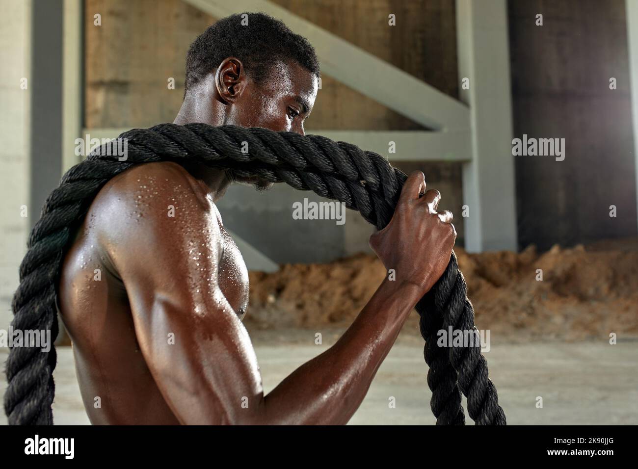 Rope workout. Sport man doing battle ropes exercise outdoor. Black male athlete exercising