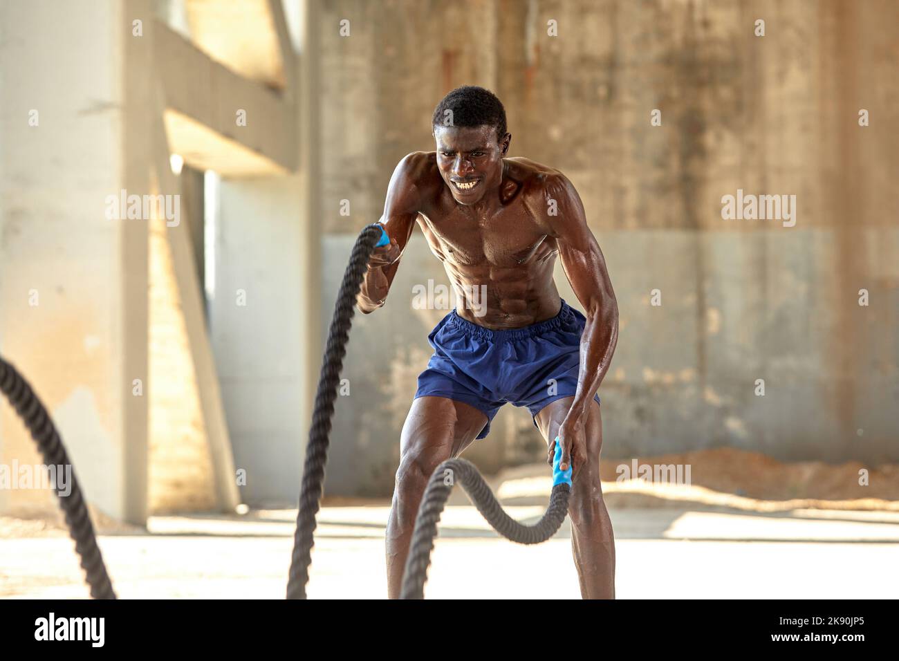 Rope workout. Sport man doing battle ropes exercise outdoor. Black male athlete exercising