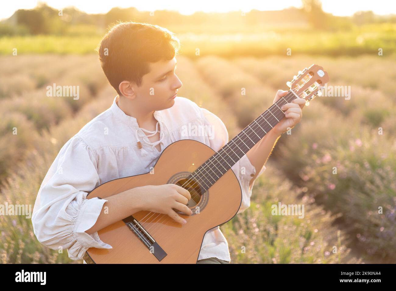 The young man playing the guitar in the lavender field Stock Photo