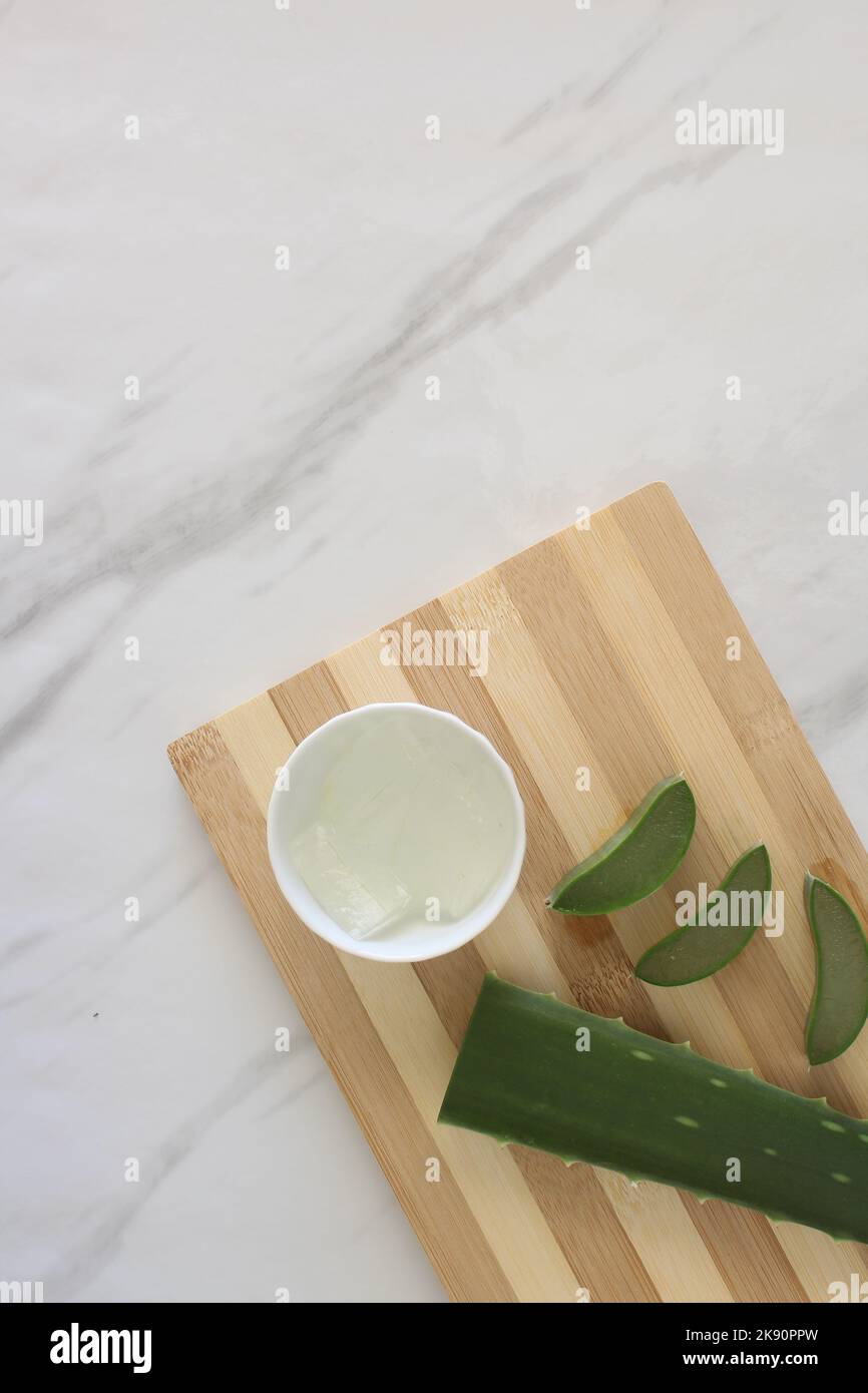 Pieces of aloe vera and a bowl of aloe vera gel on cutting board Stock