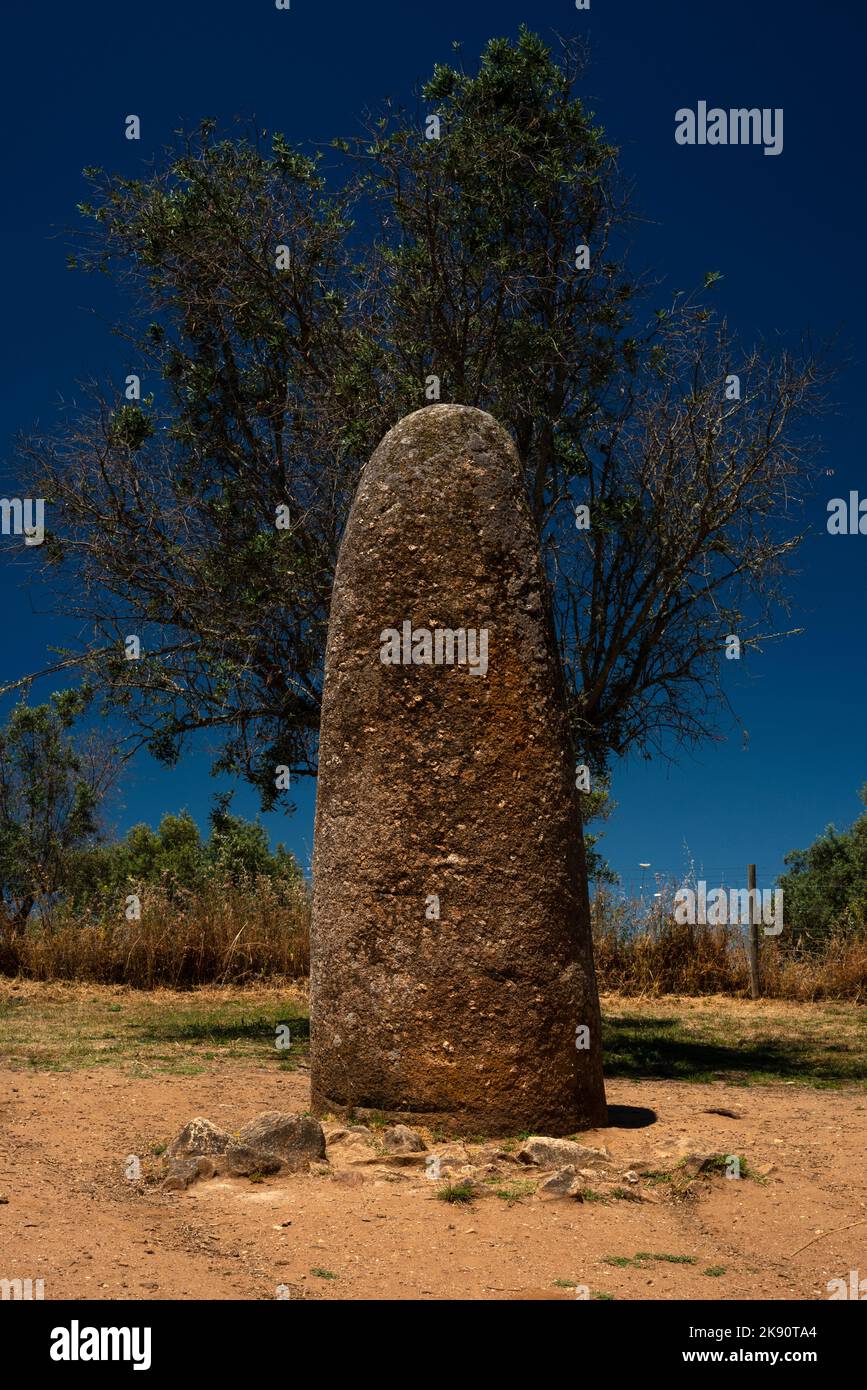 The Menir dos Almendres, a lone standing stone about 4 meters (13 ft) high, pointed to the summer solstice sunrise when it was viewed by prehistoric people about 1.4 km away amid the megalith rings of the Almendres Cromlech, founded some 7,000 years ago near today’s city of Évora, Alentejo Central, Portugal. Stock Photo