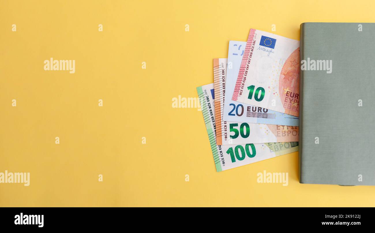 Different euro banknotes next to a notepad on a yellow background, Expense and budget planning. Cash paper currency, payment, earnings and savings, th Stock Photo