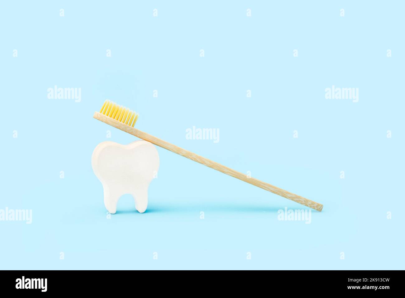 Bamboo wood toothbrush with yellow brush bristles and a white teeth on ...