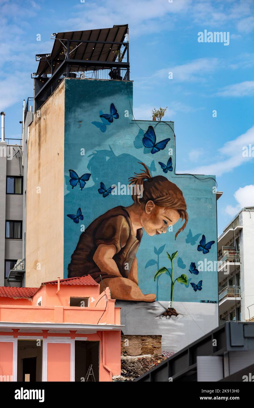 A vertical shot of a beautiful street art of a little girl on the sidewall of a building in Athens Stock Photo