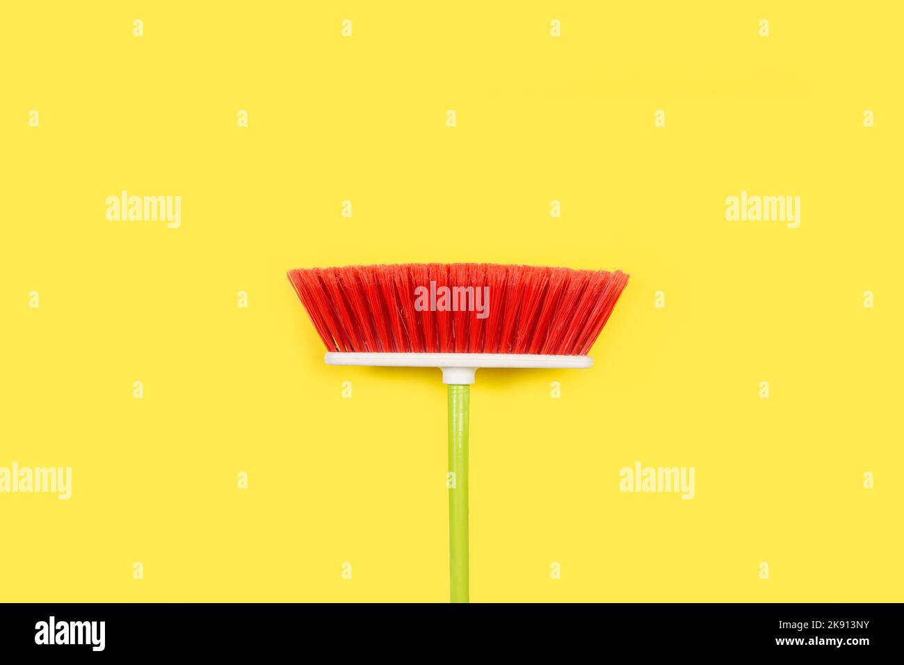 A red broom on a yellow background with copy space Stock Photo