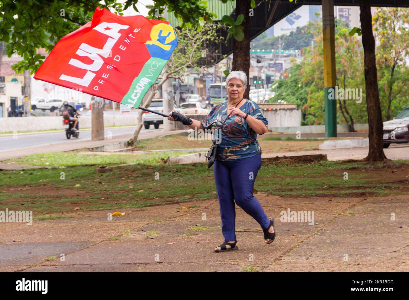Goiânia, Goias, Brazil – October 21, 2022: A woman walking holding a Lula flag. Image made in an act to ask for votes for Lula. Stock Photo