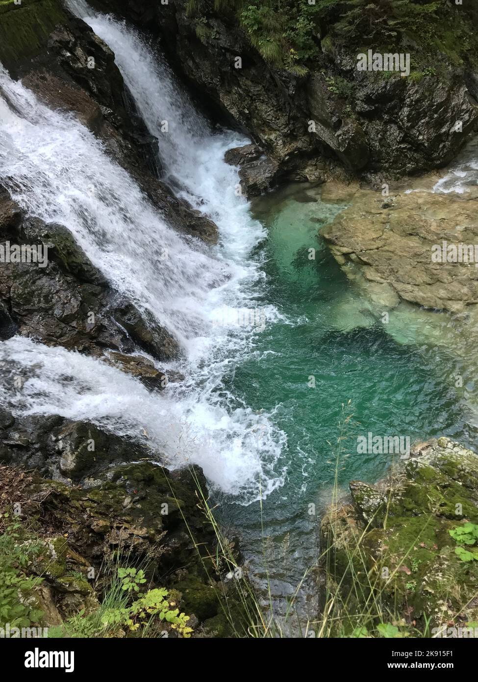 A vertical top view of a waterfall falling into a rocky plunge pool