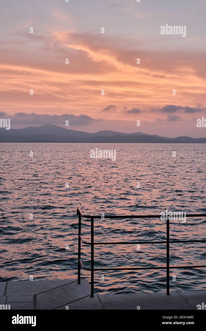 The sun sets over the Adriatic sea seen from the coast of Zadar in Croatia described by Alfred Hitchcock Stock Photo